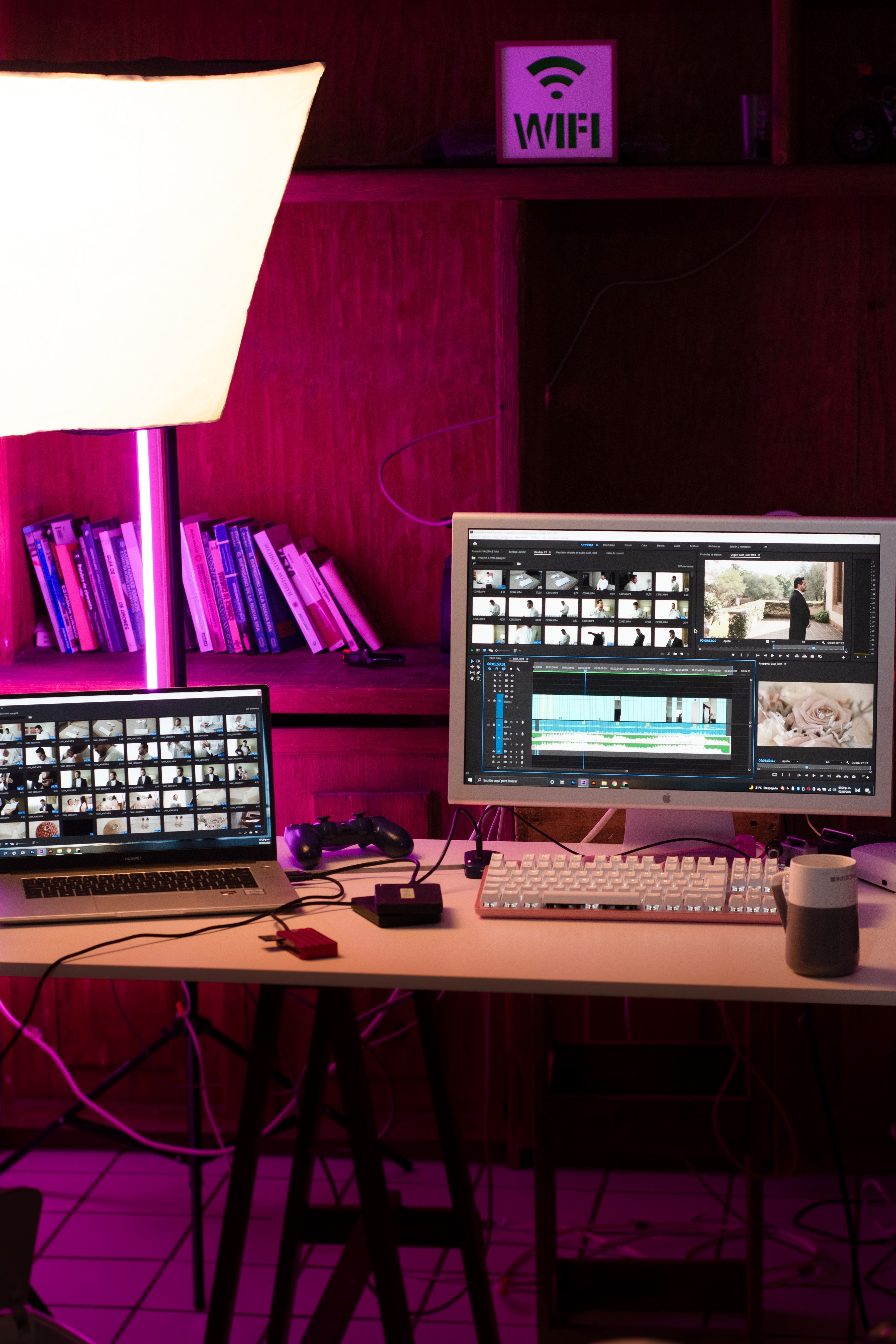 A modern home office setup featuring a laptop and dual monitors for video editing under soft lighting.