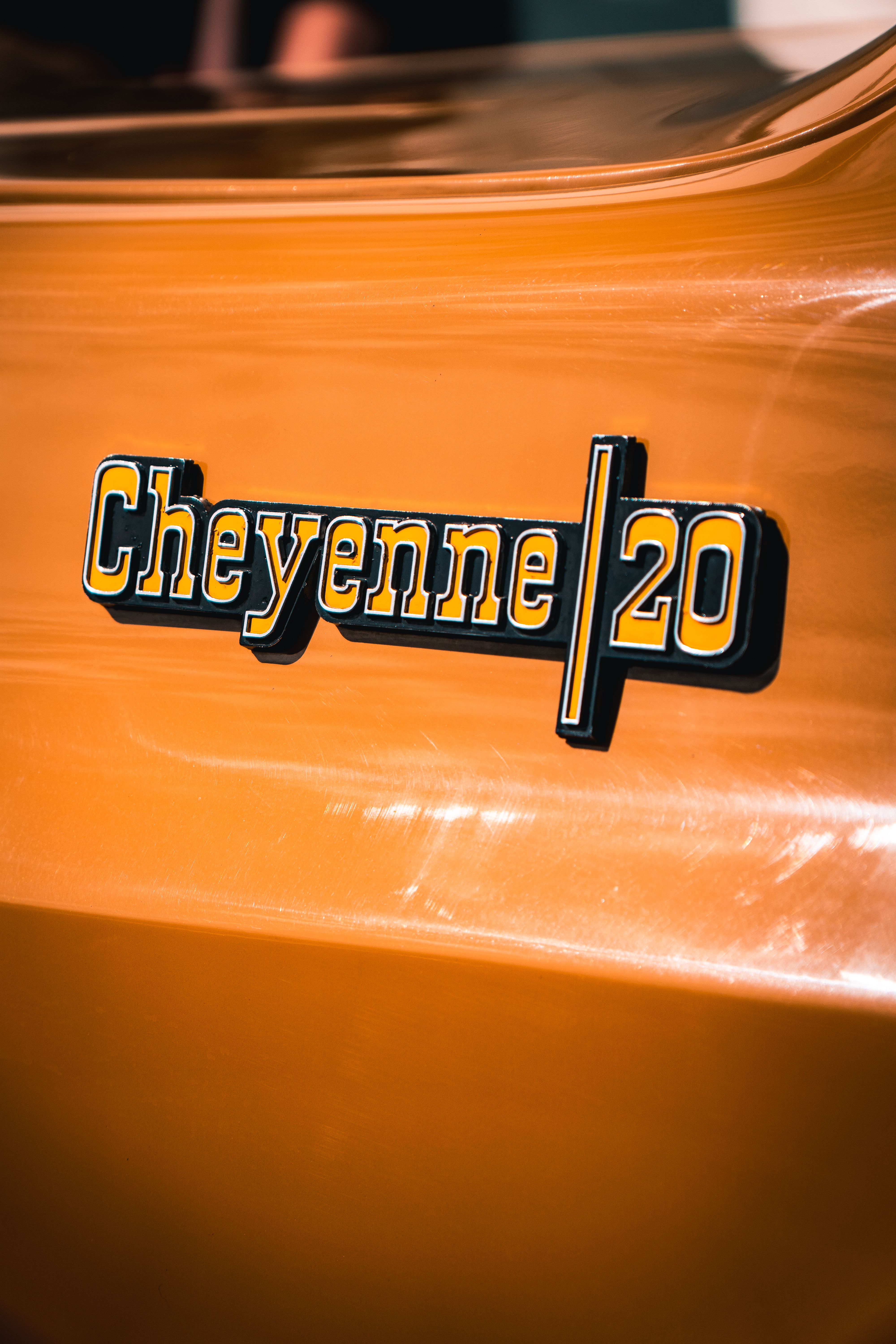 Detailed view of a classic Cheyenne 20 emblem on a yellow vintage vehicle.
