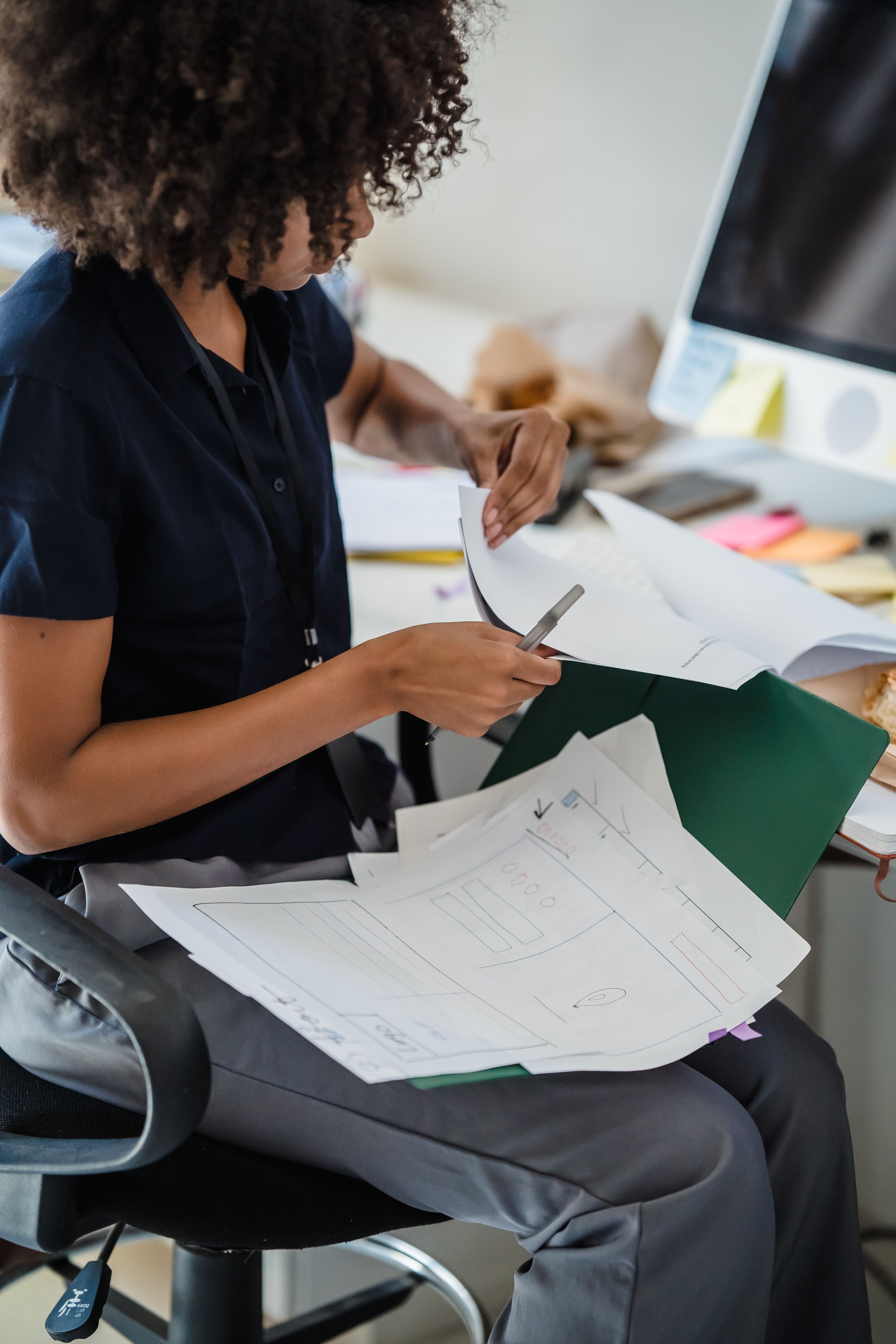 Businesswoman organizing documents at her office desk for efficient workflow.