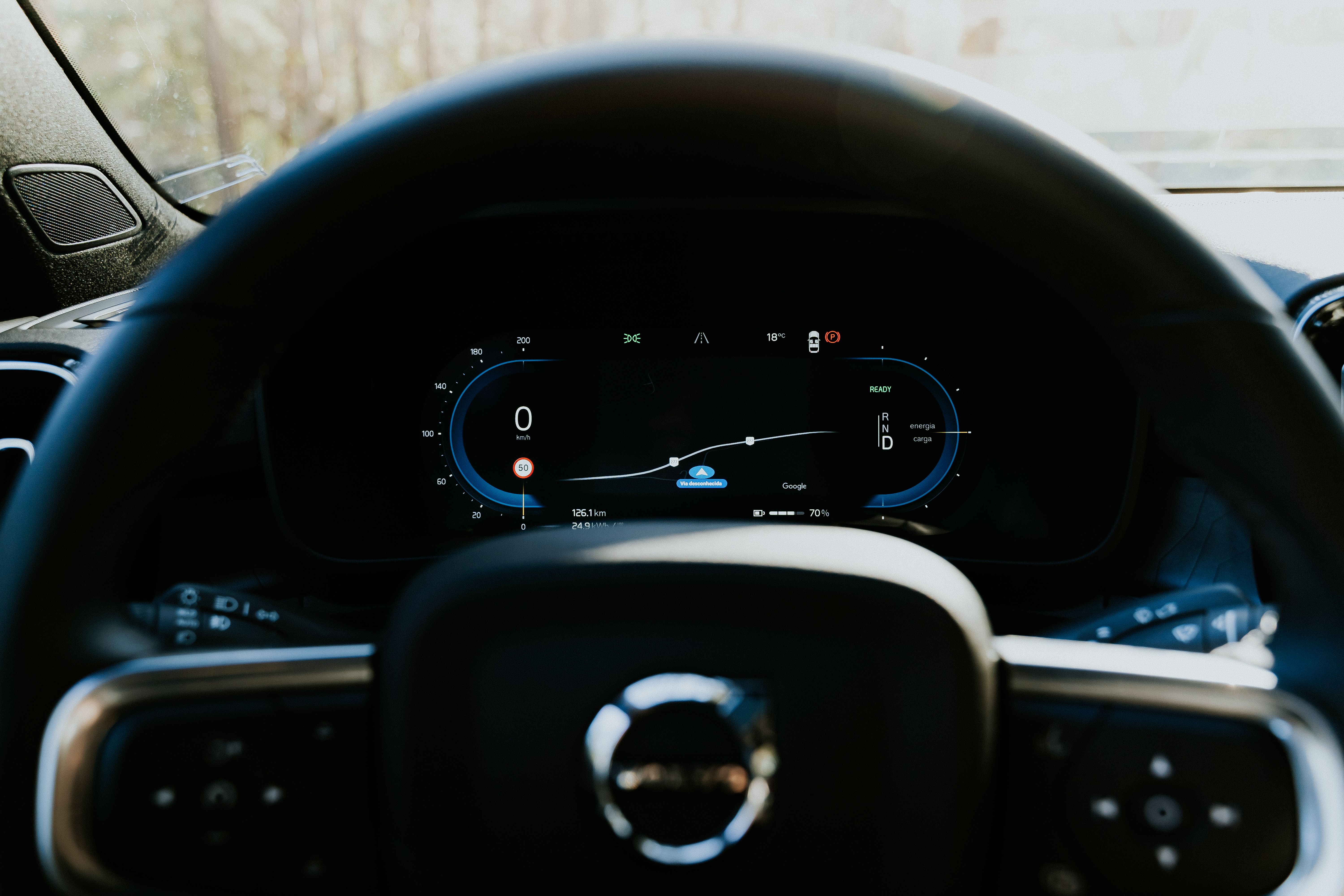 Close-up of a Volvo car steering wheel with digital dashboard display, showcasing modern automotive technology.