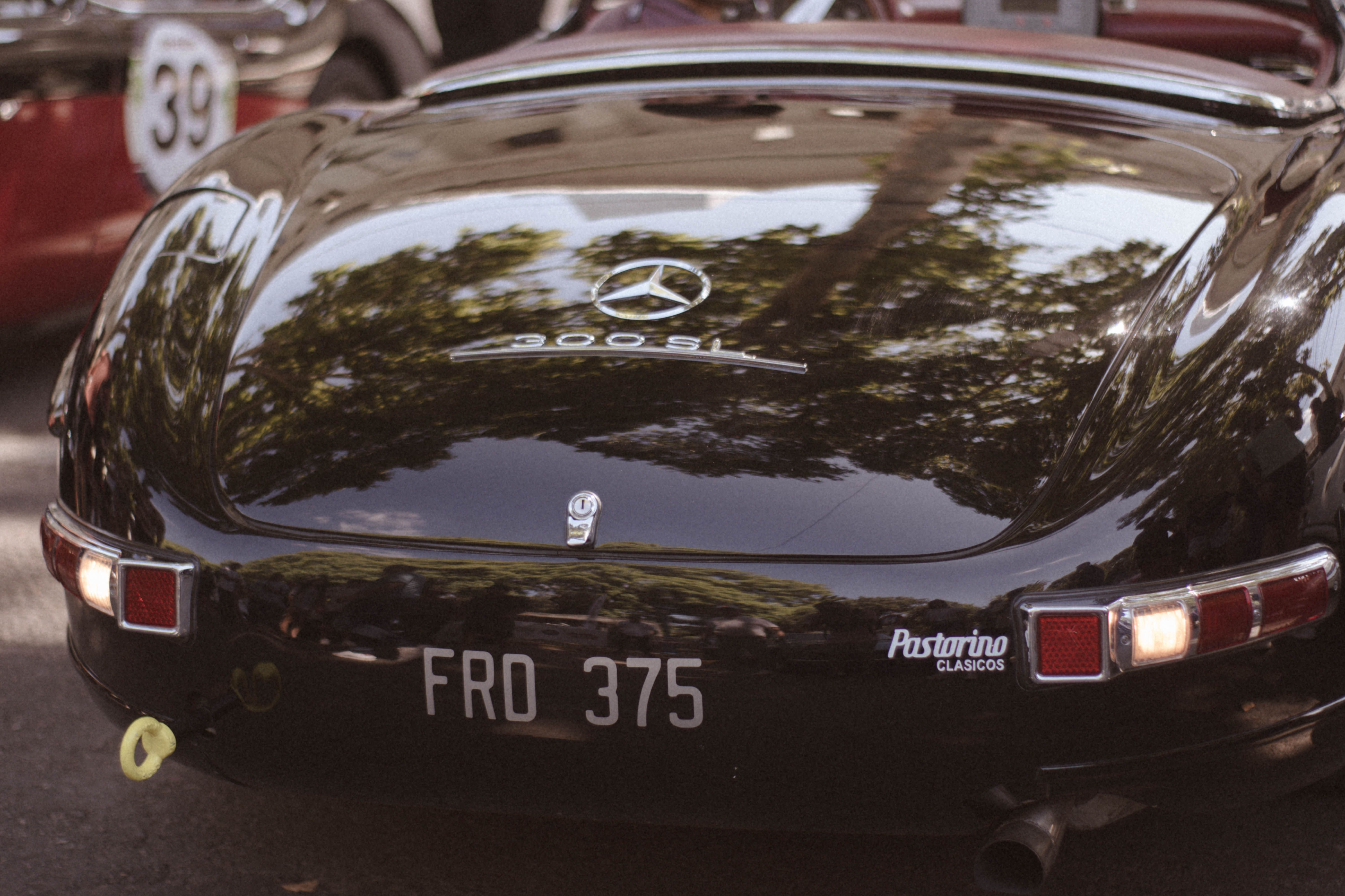 Vintage Mercedes 300 SL with reflections at an outdoor car show, highlighting classic automotive design.