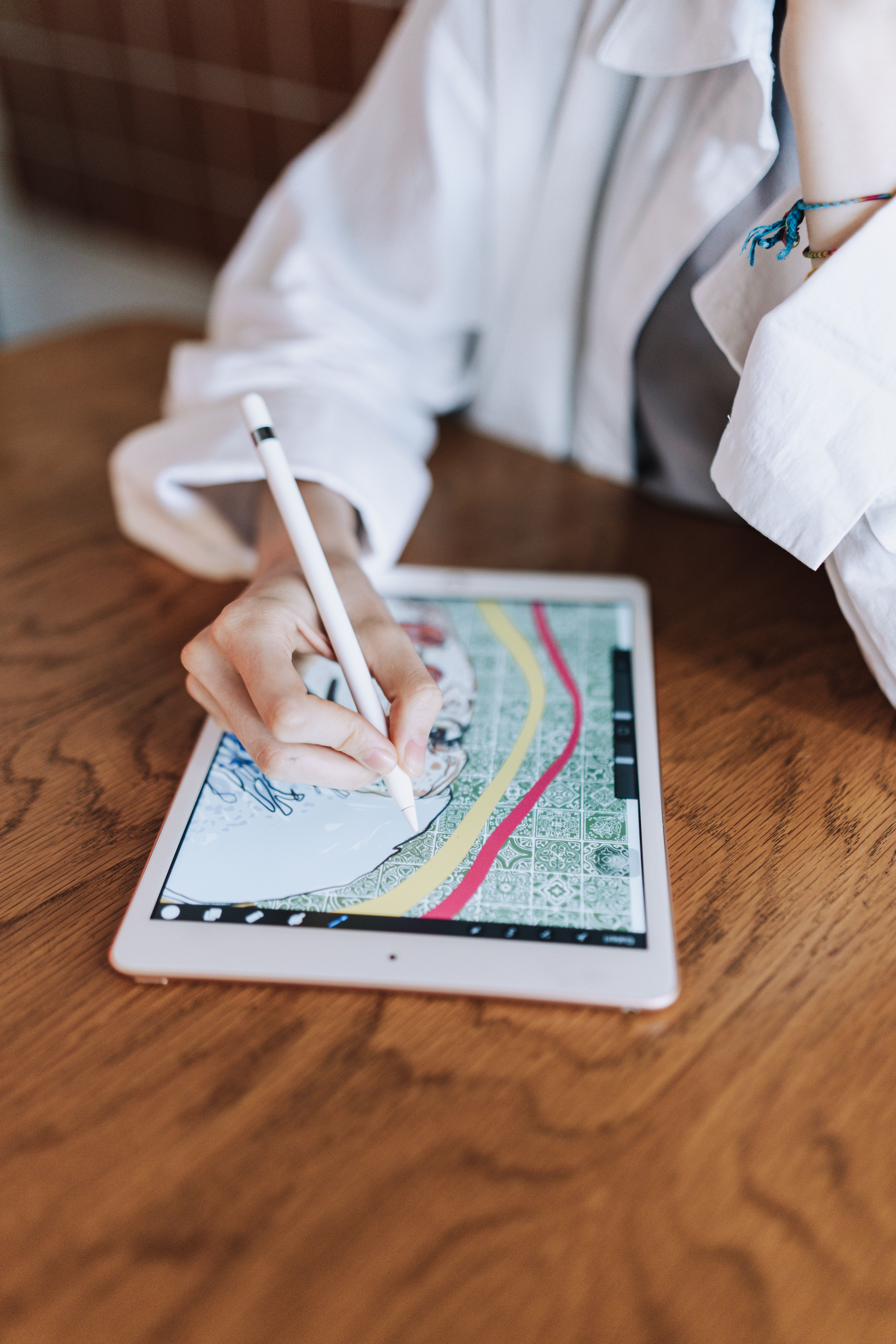 Woman sketching intricate design on tablet with stylus in contemporary indoor setting.