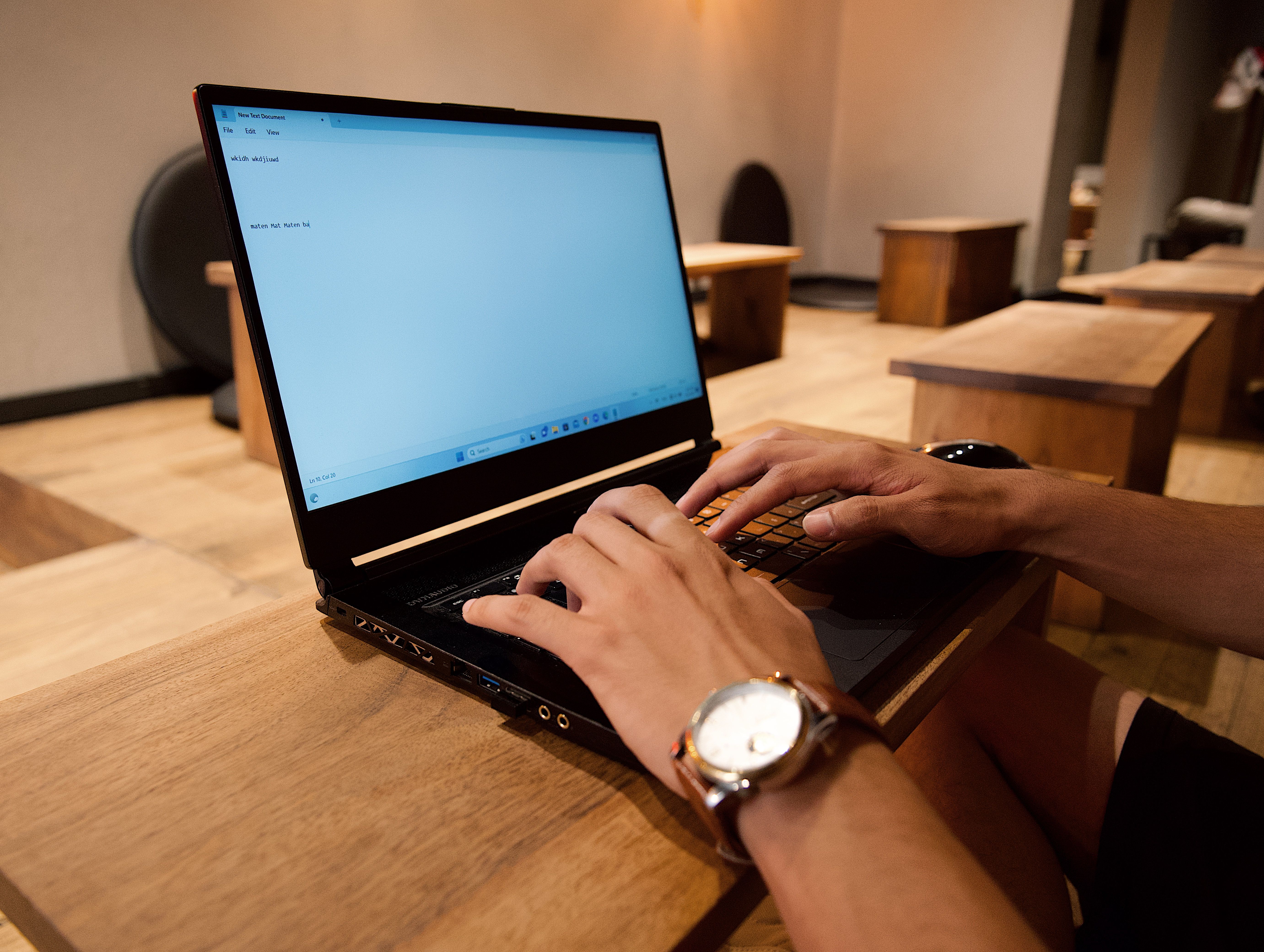 A person working on a laptop in a modern office setting, focused on typing.