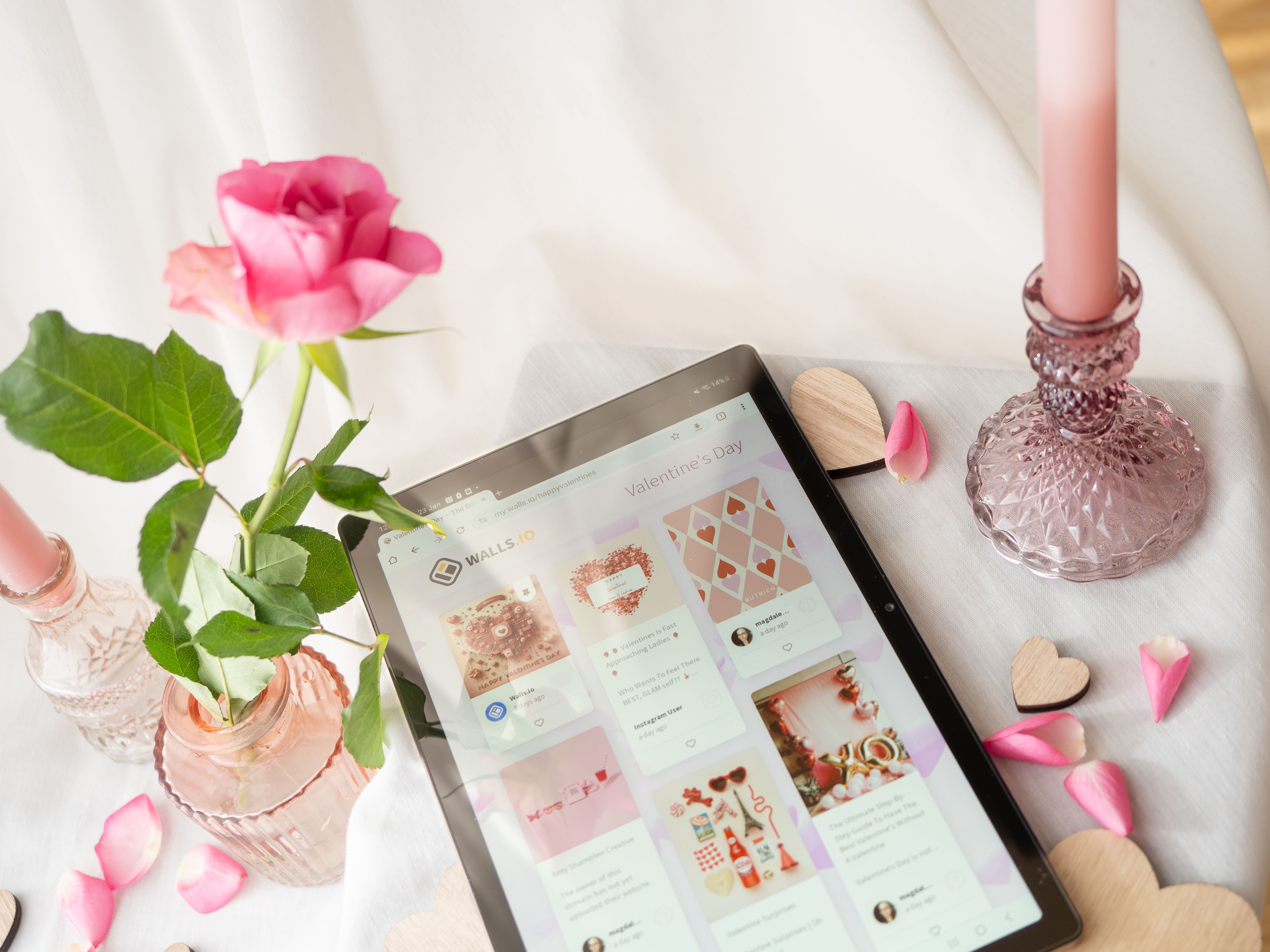 Elegant table setup featuring a tablet, pink rose, and candle. Perfect for romantic and tech-themed compositions.