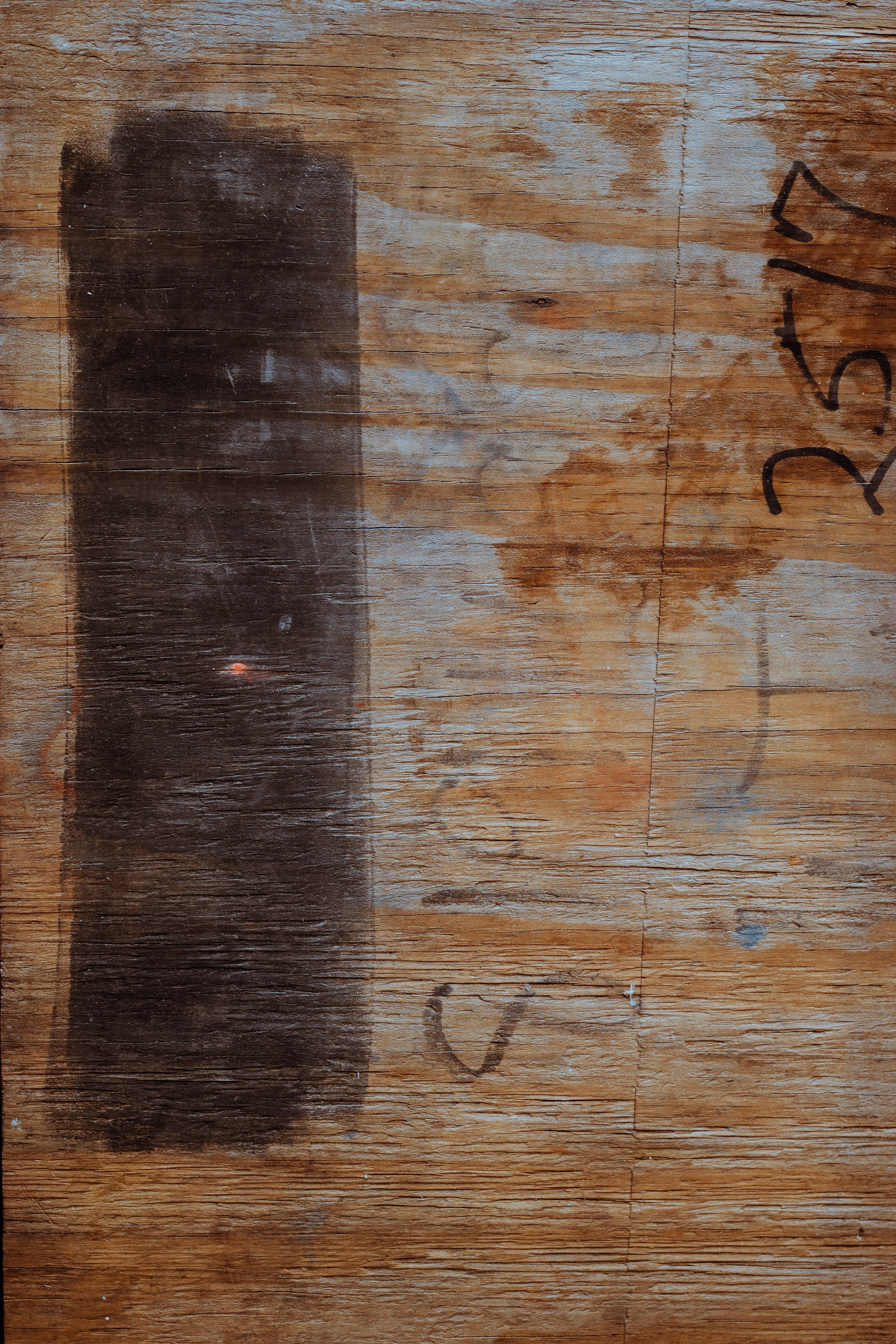 Detailed close-up of a textured wooden surface with dark paint and unique markings.