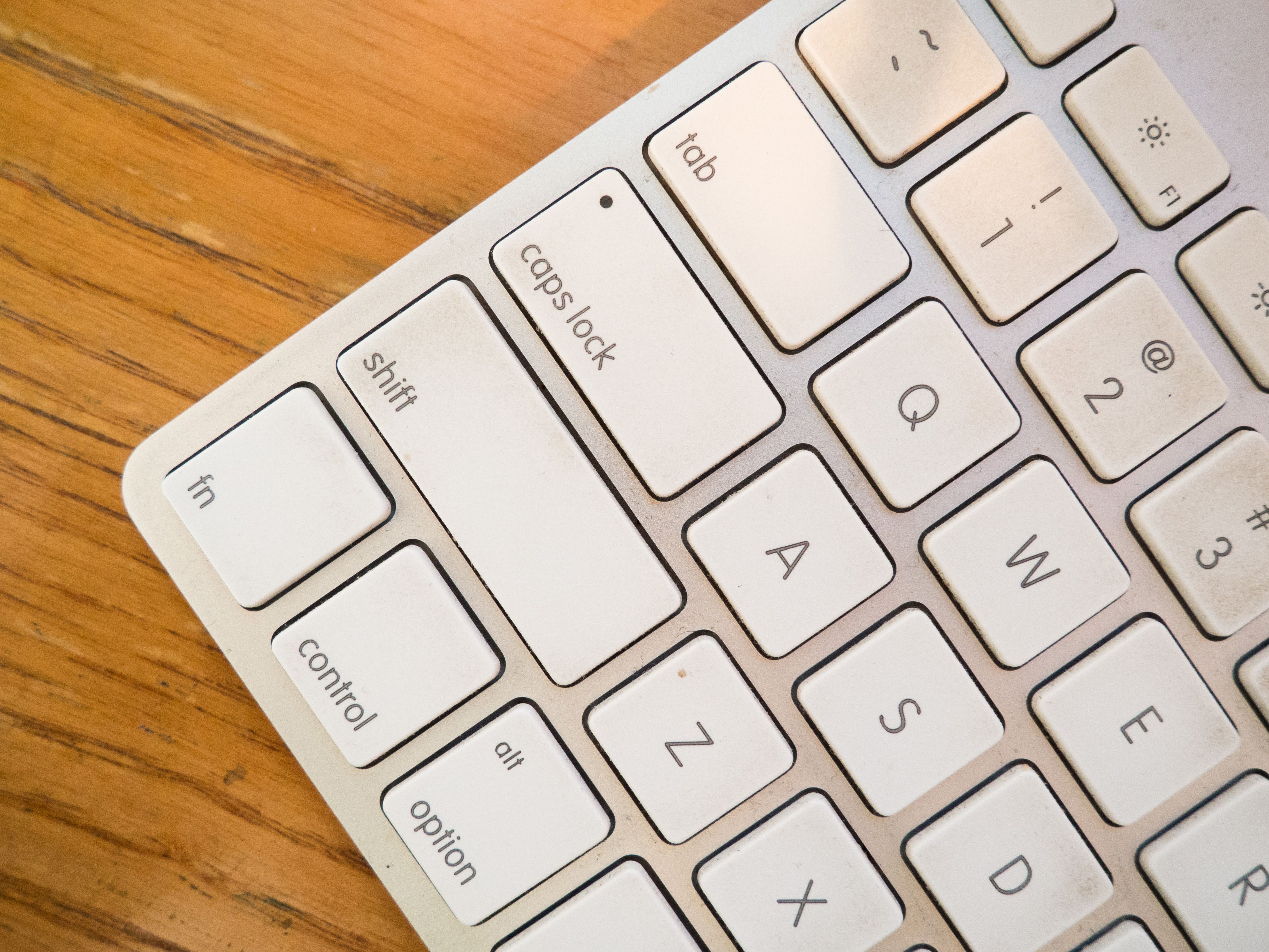 A detailed close-up of a modern computer keyboard on a wooden desk.