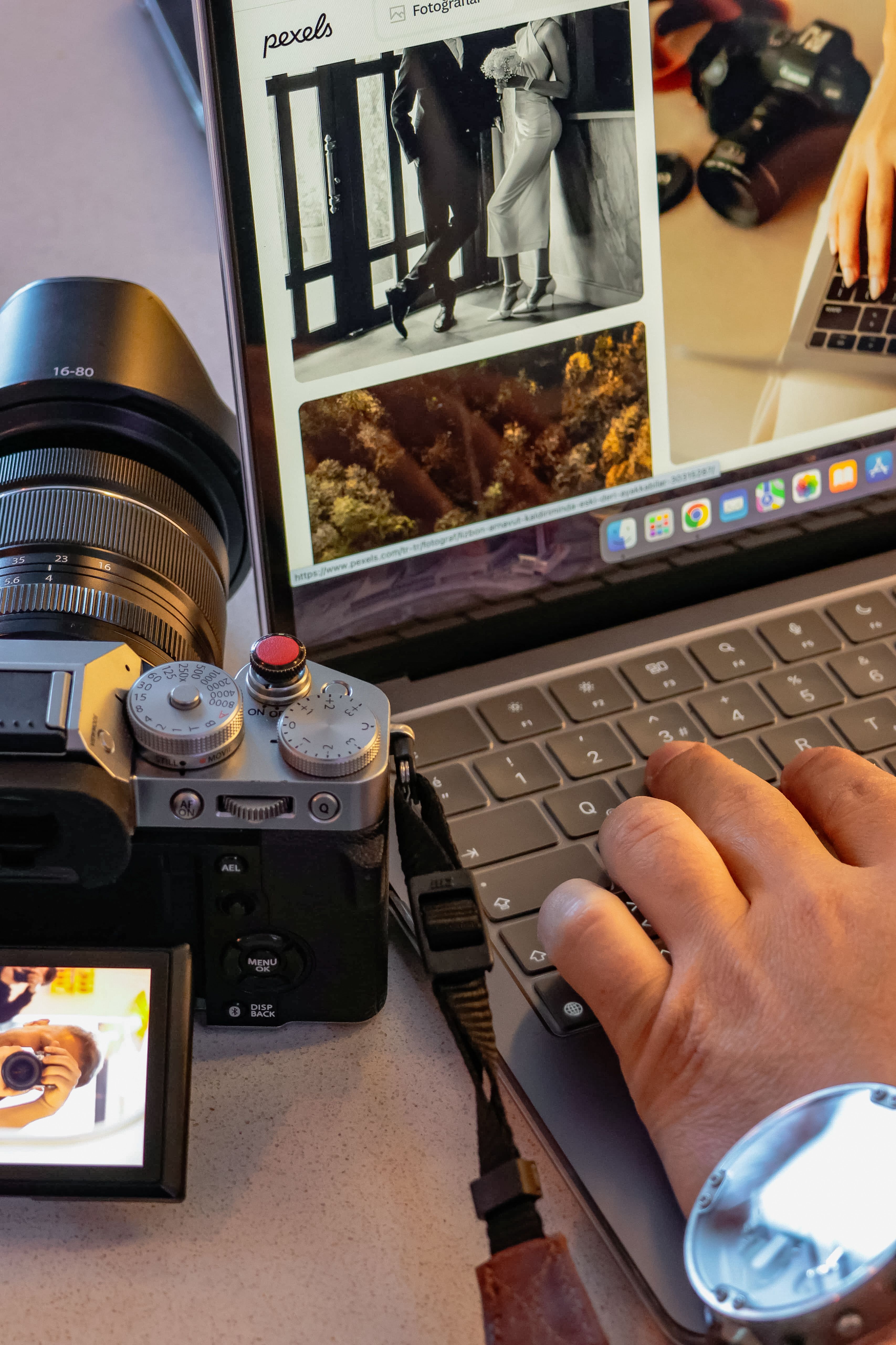 Close-up of photographer editing photos on a laptop with a camera nearby.