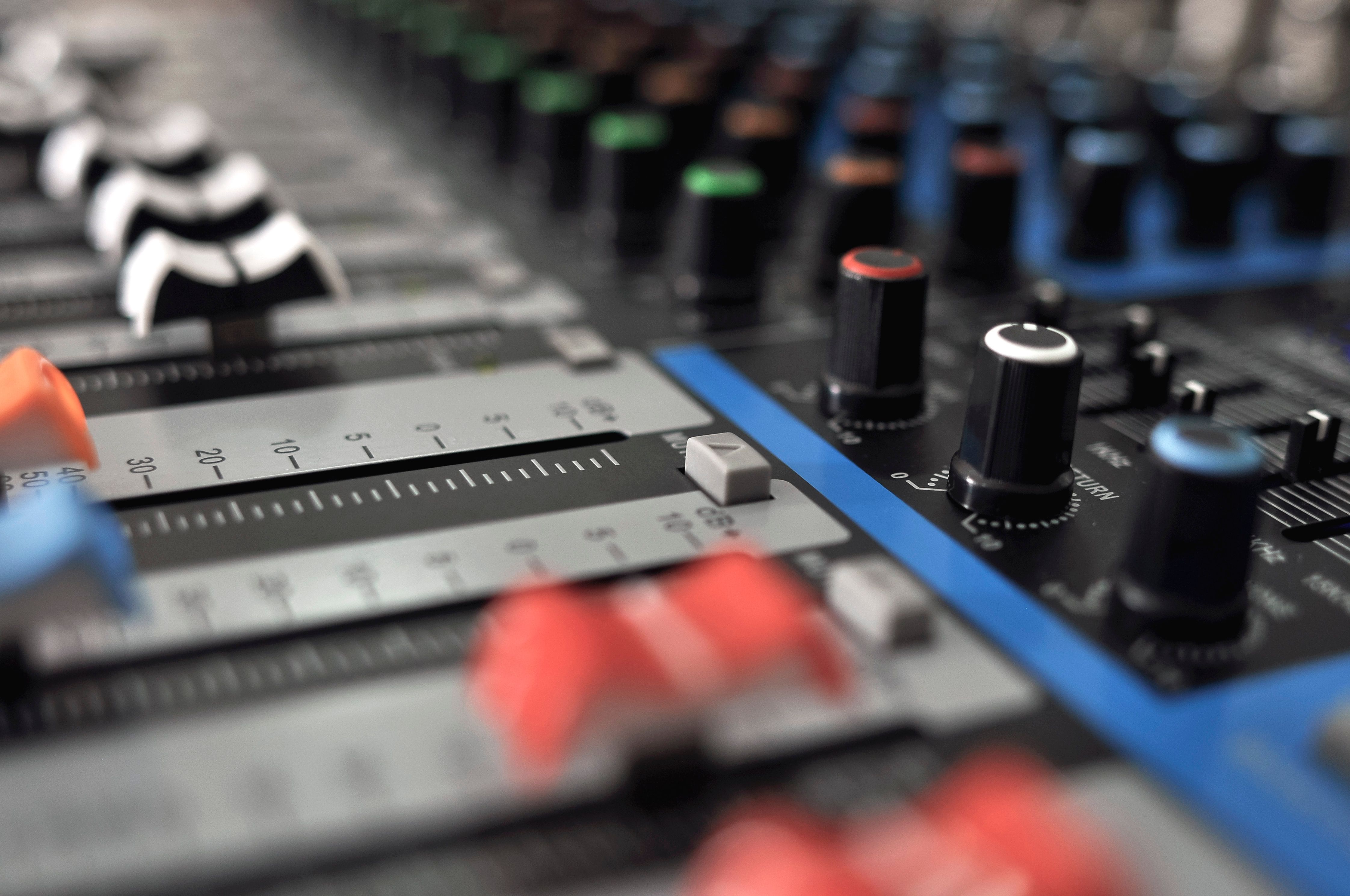 Detailed close-up of an audio mixing console with colorful knobs and sliders.