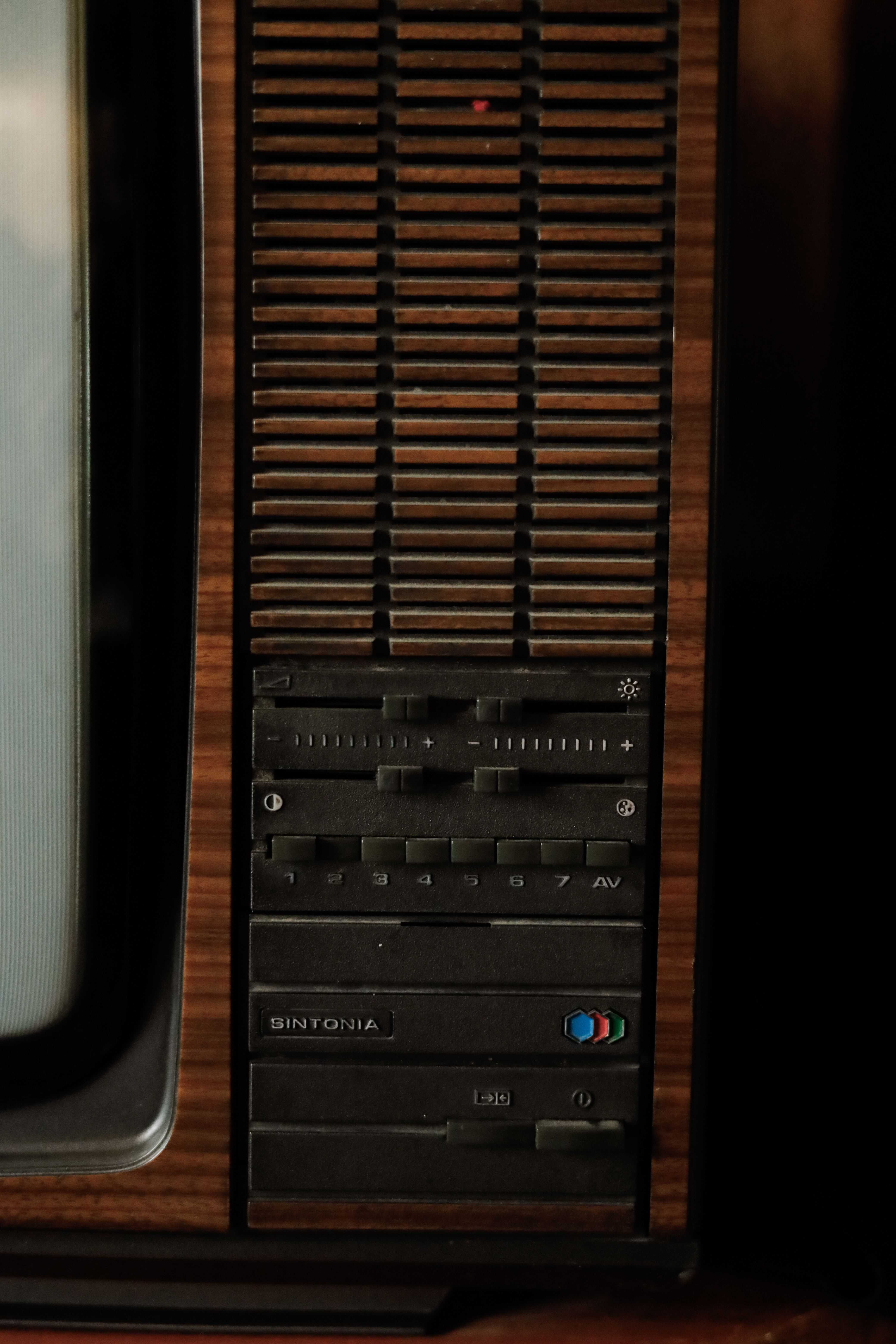 Close-up of a vintage TV's side panel featuring retro controls and wood paneling.