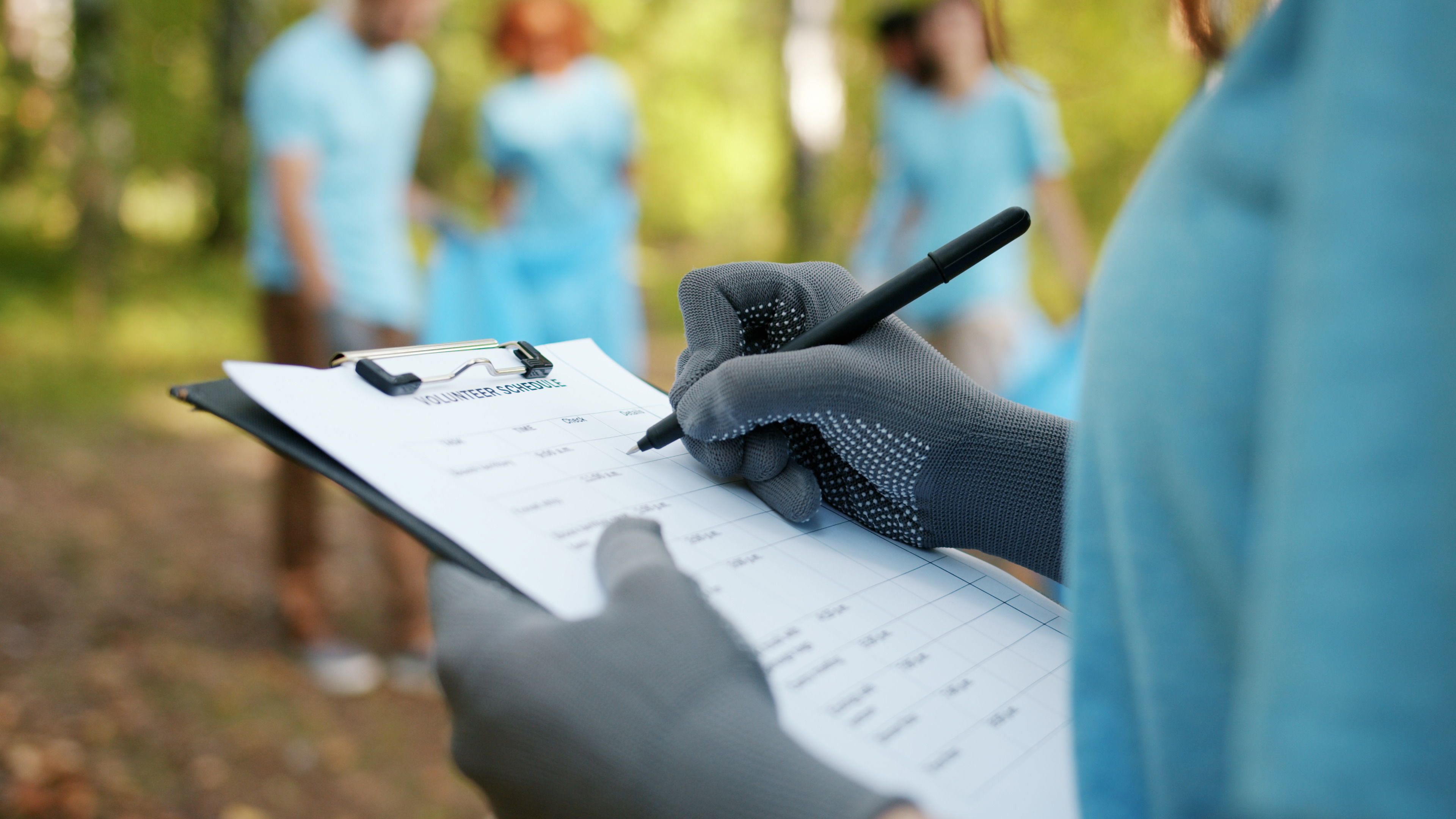Volunteer using a clipboard to organize tasks during an outdoor cleanup event.