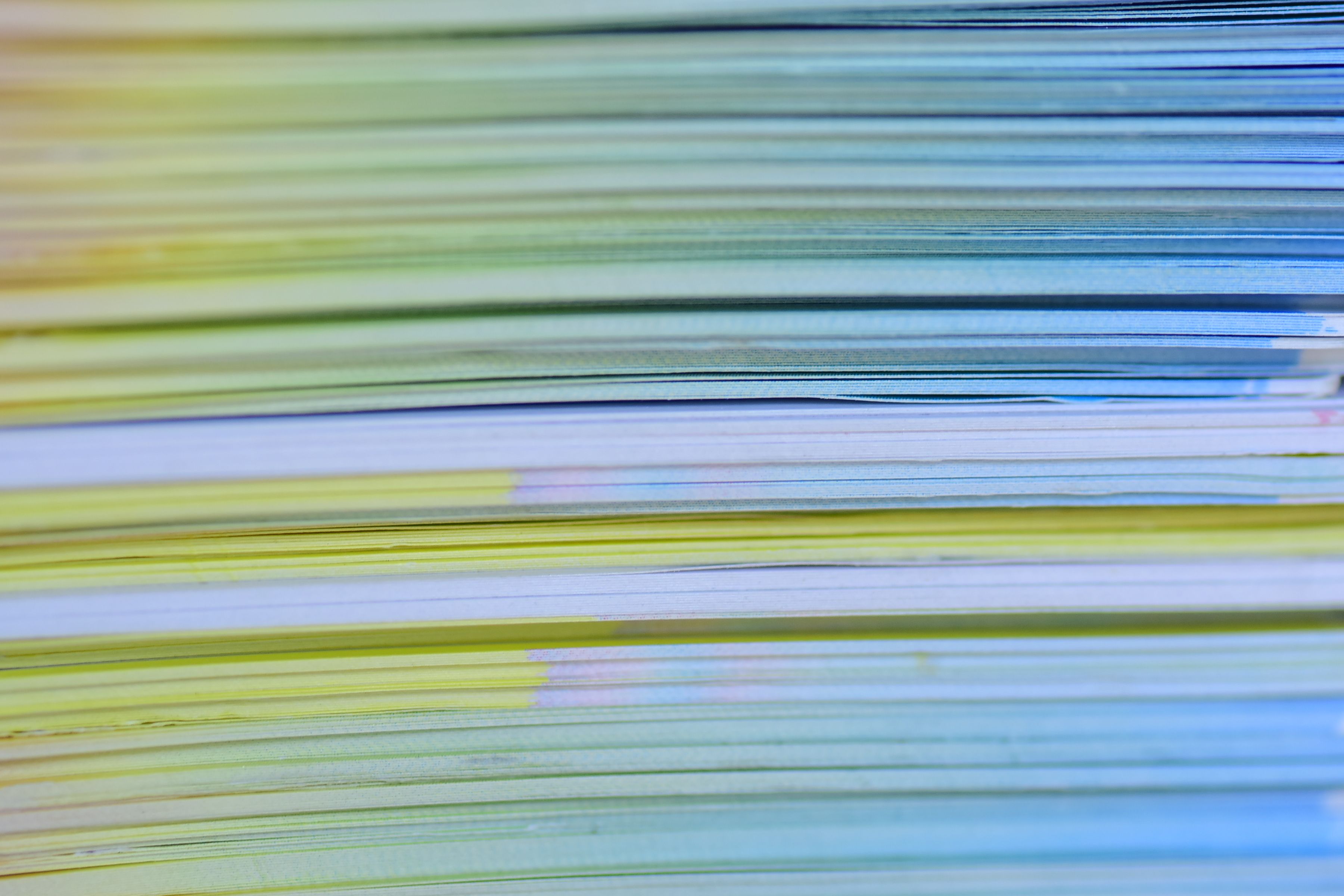 Close-up photo of a colorful stack of papers creating a vibrant abstract pattern.