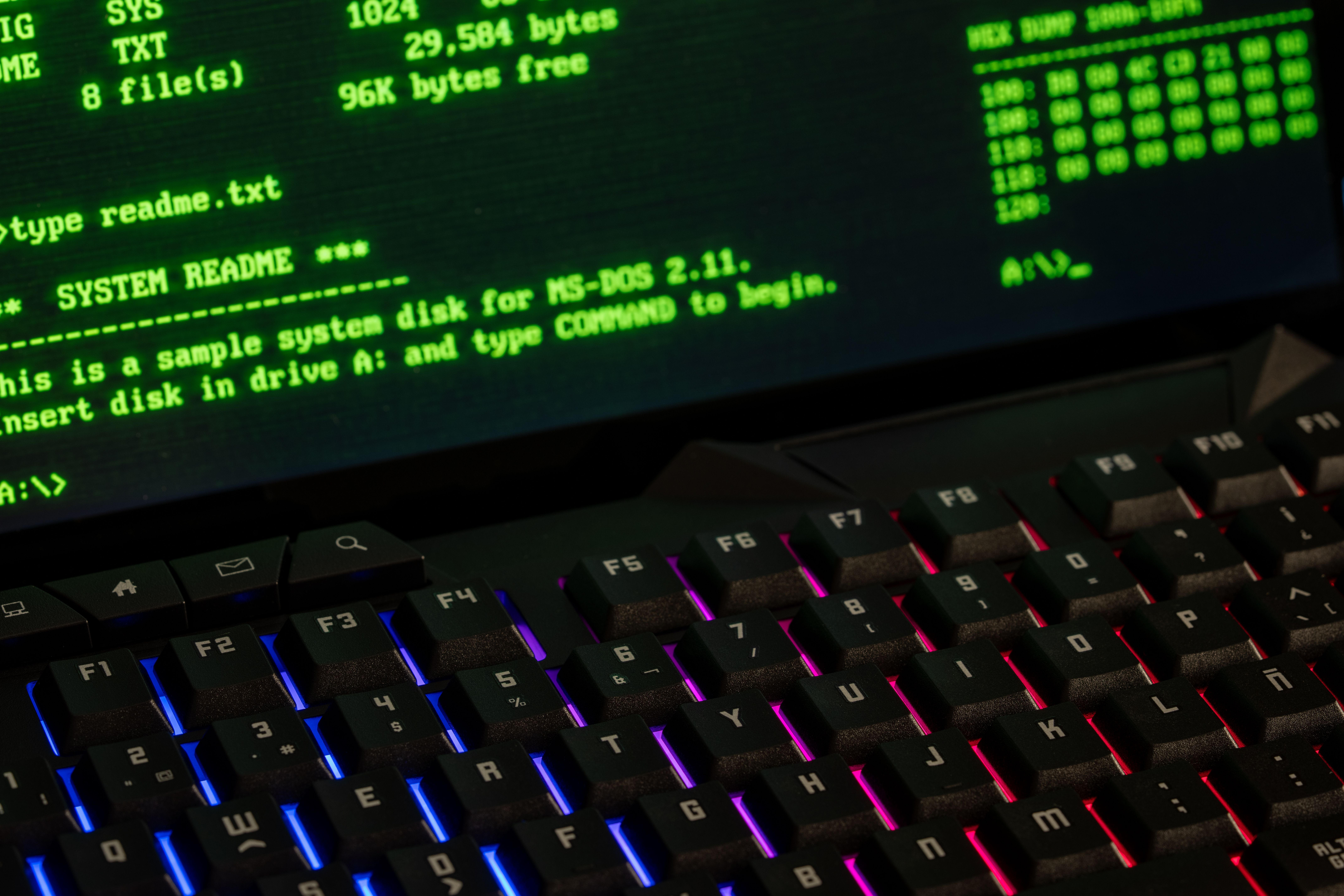 Close-up of a retro computer screen displaying MS-DOS commands with a vibrant keyboard.