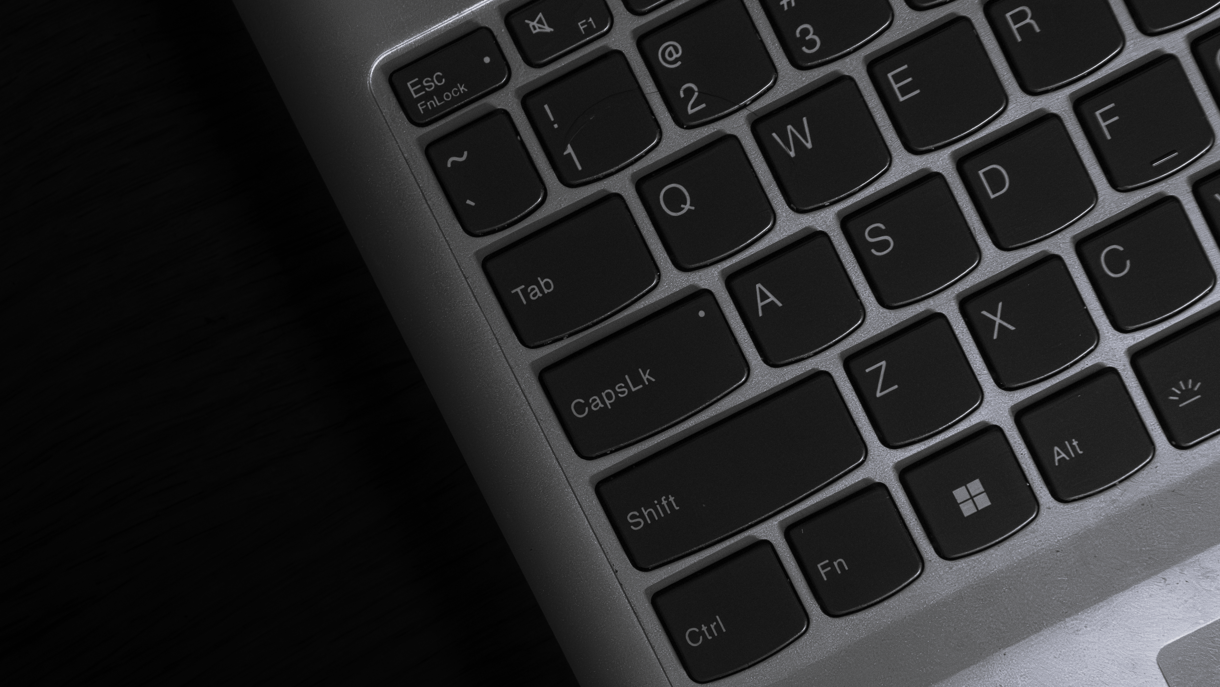 Black laptop keyboard detail, featuring keys and backlighting contrast.