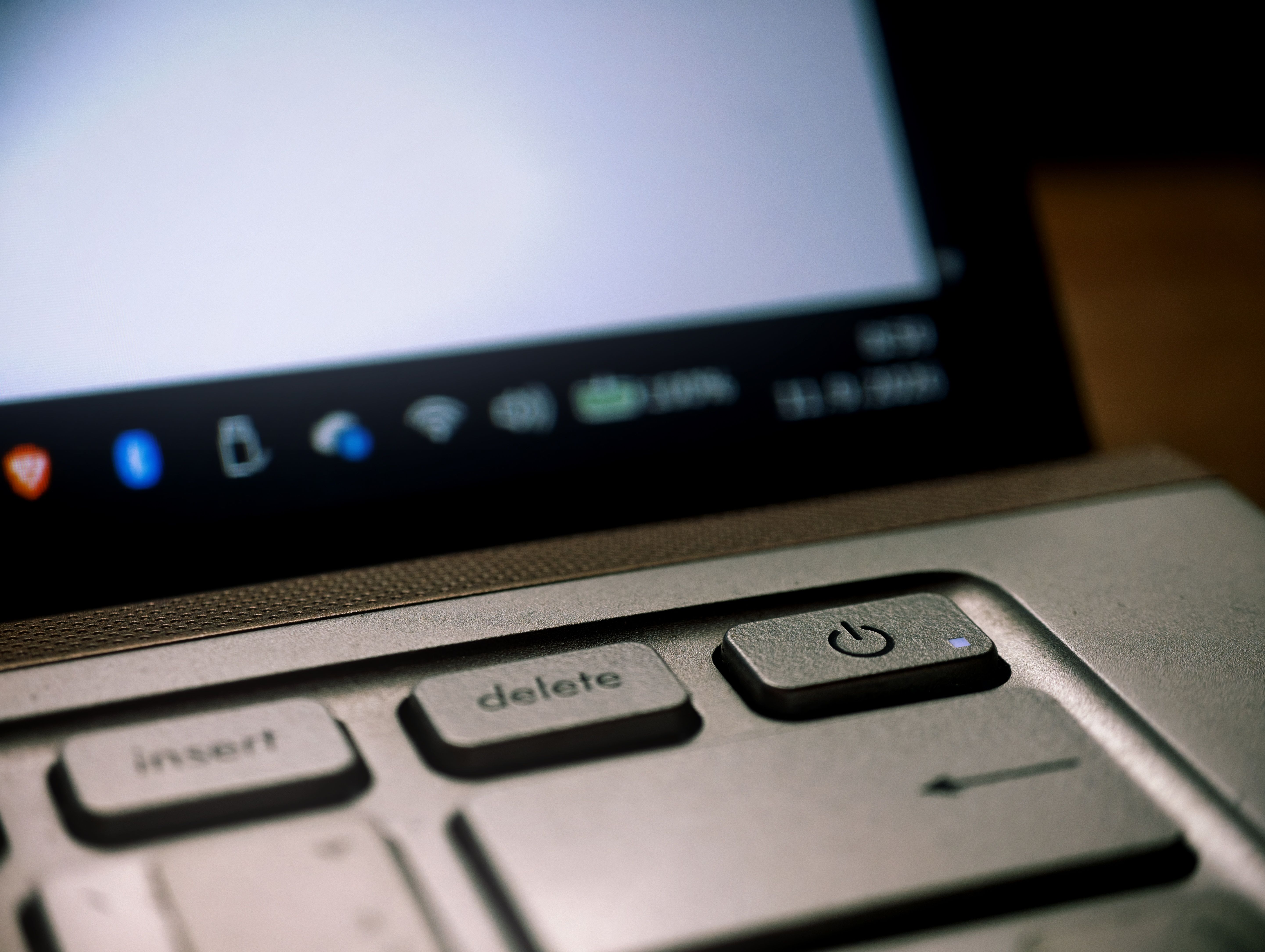 Detailed shot of laptop keyboard focusing on the power button and keys in dim lighting.