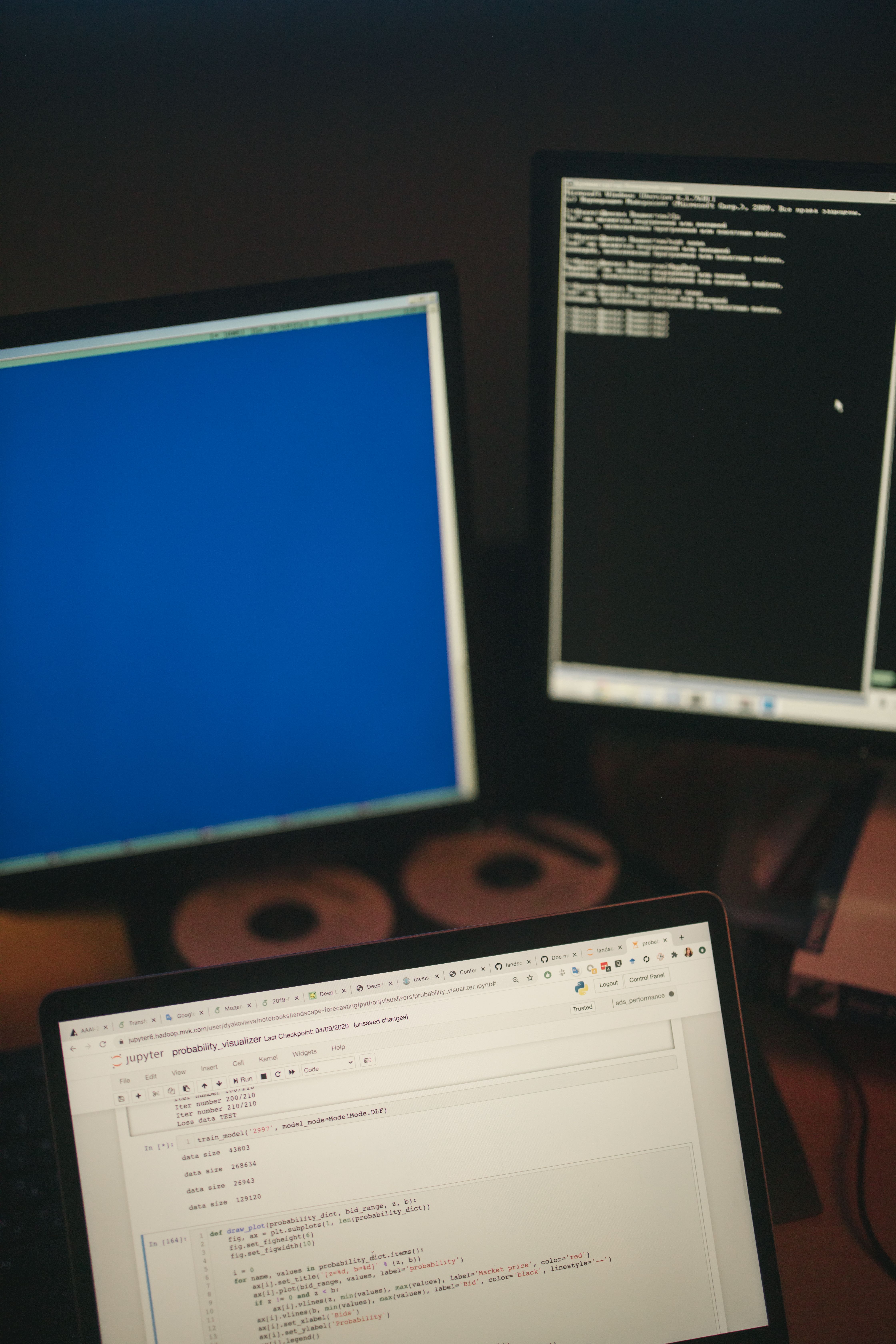 A multi-screen workstation showcasing coding on monitors and a laptop.