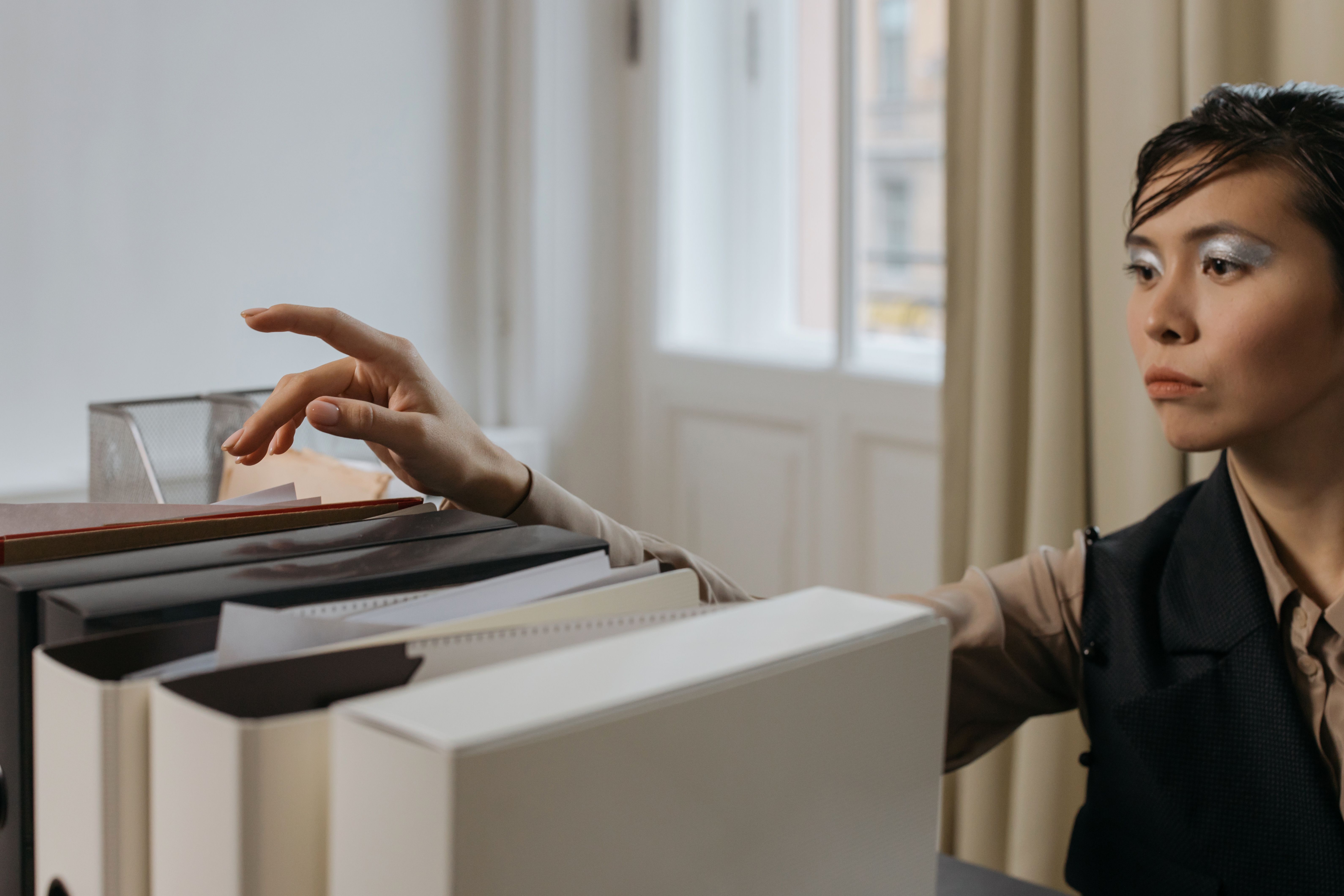 A stylish woman organizes documents in a modern office setting.