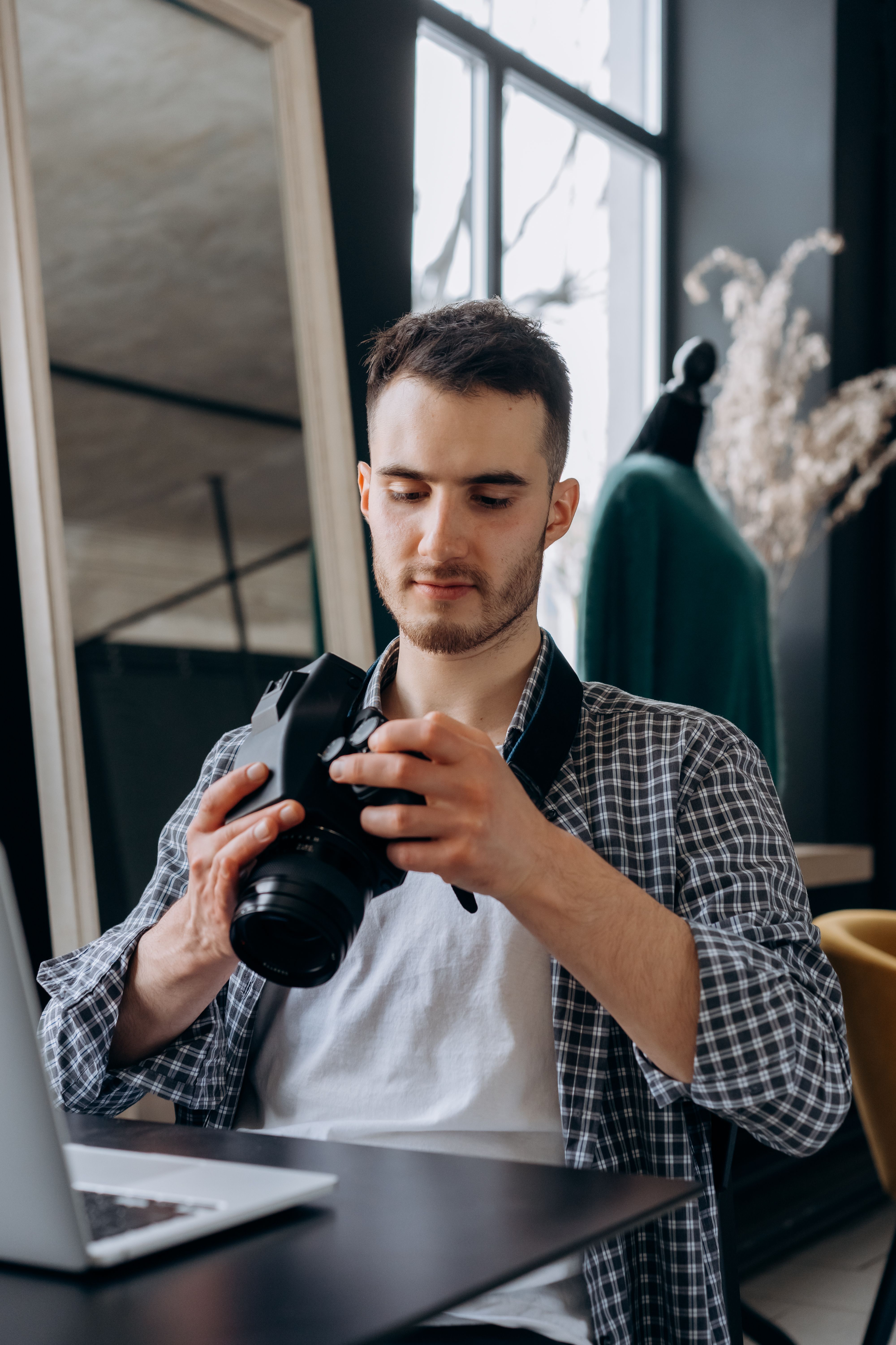 Man sitting indoors checking images on a DSLR camera.
