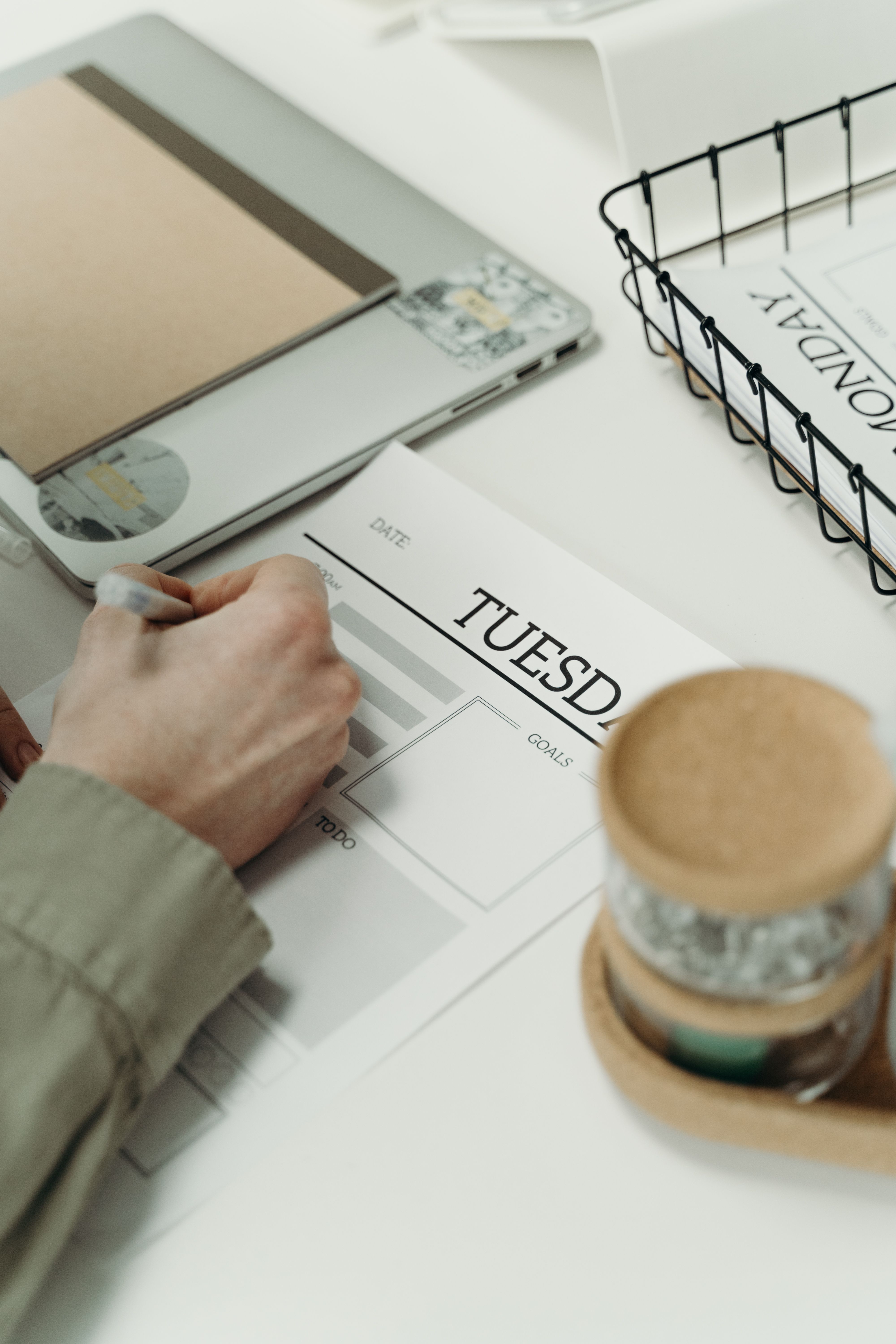 Person writing in a planner to organize weekly tasks and schedule.