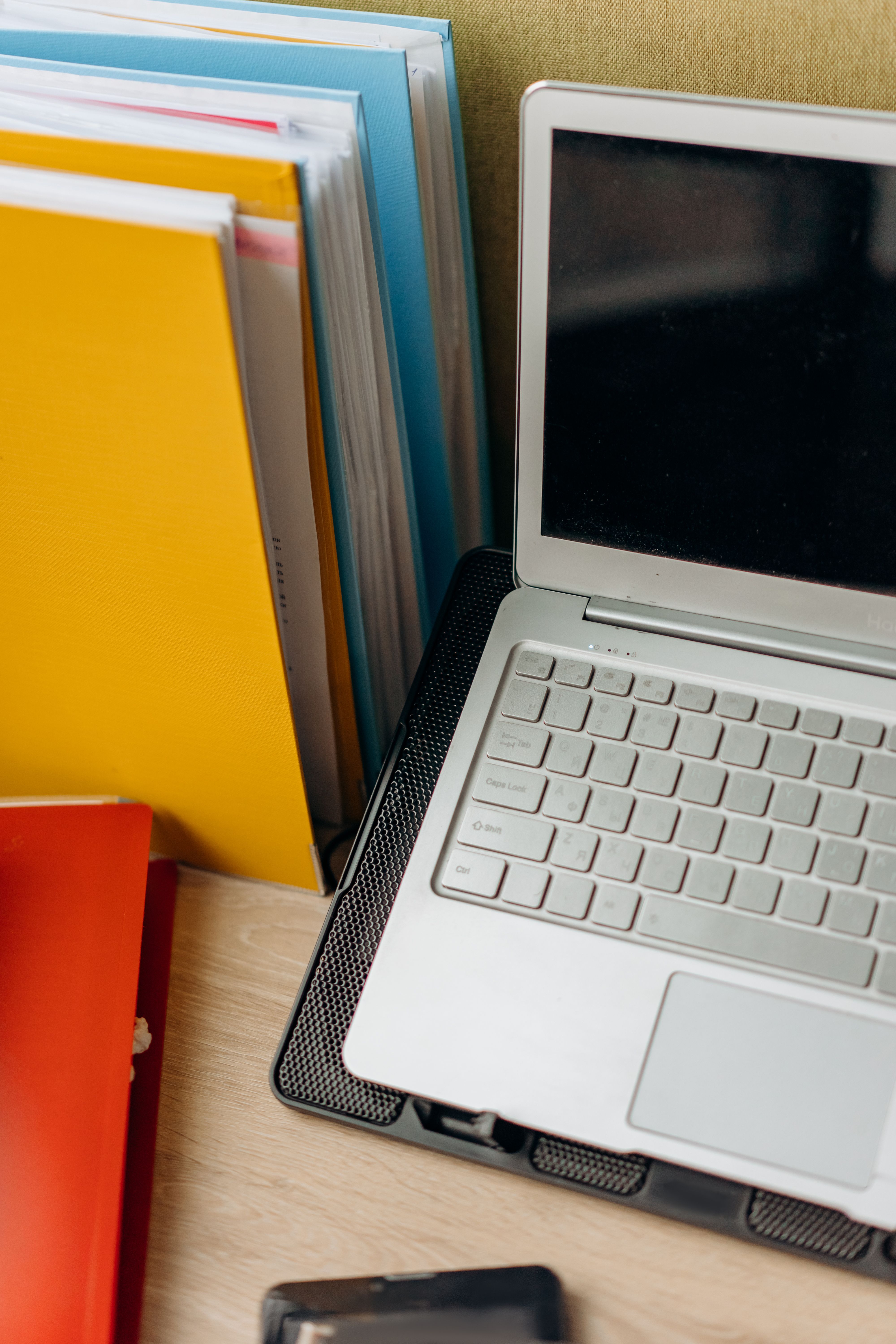 A neat office setup featuring a laptop, colorful files, and a tidy desk arrangement.
