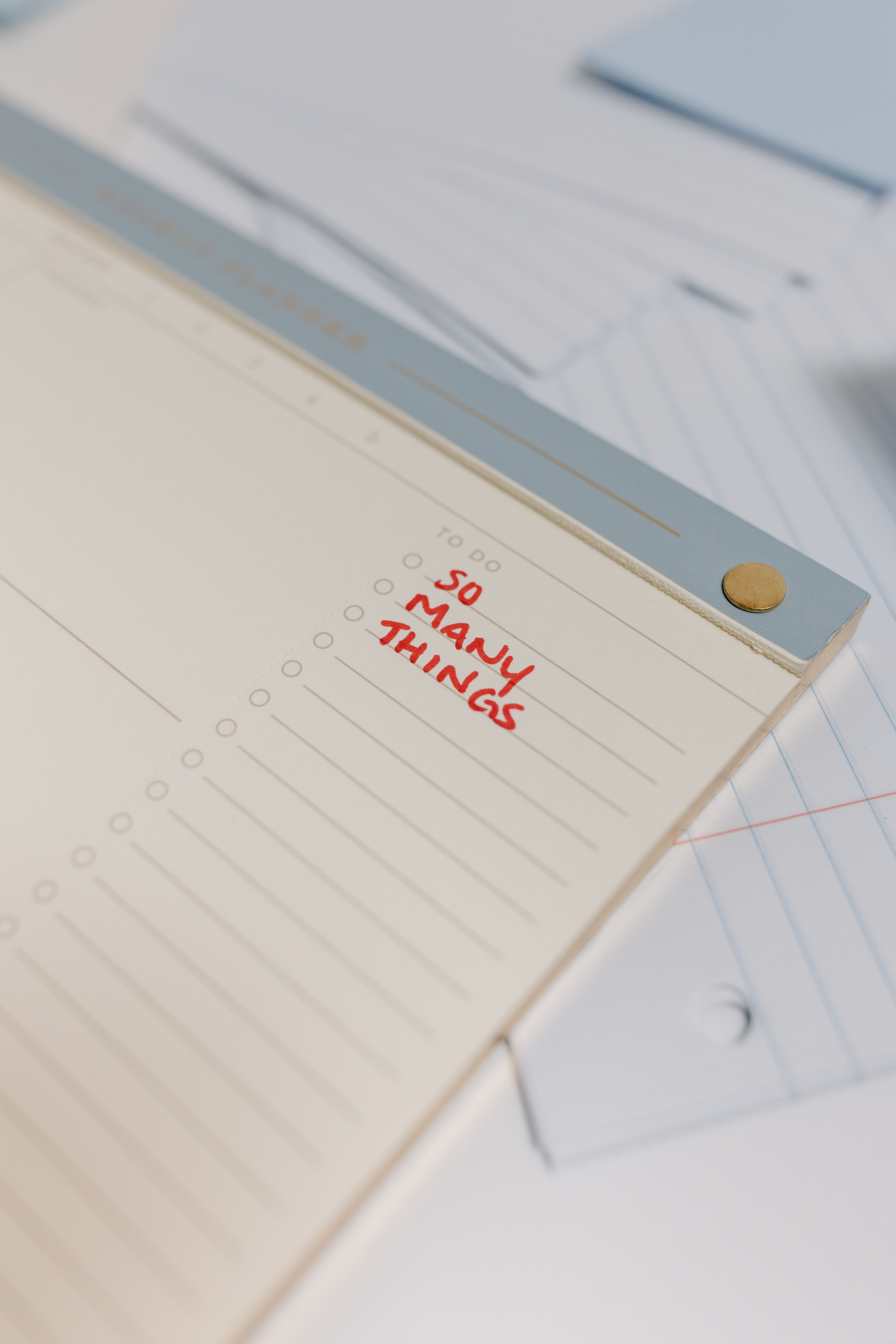 Close-up of a to-do list notepad with 'So Many Things' written, providing copyspace for text.